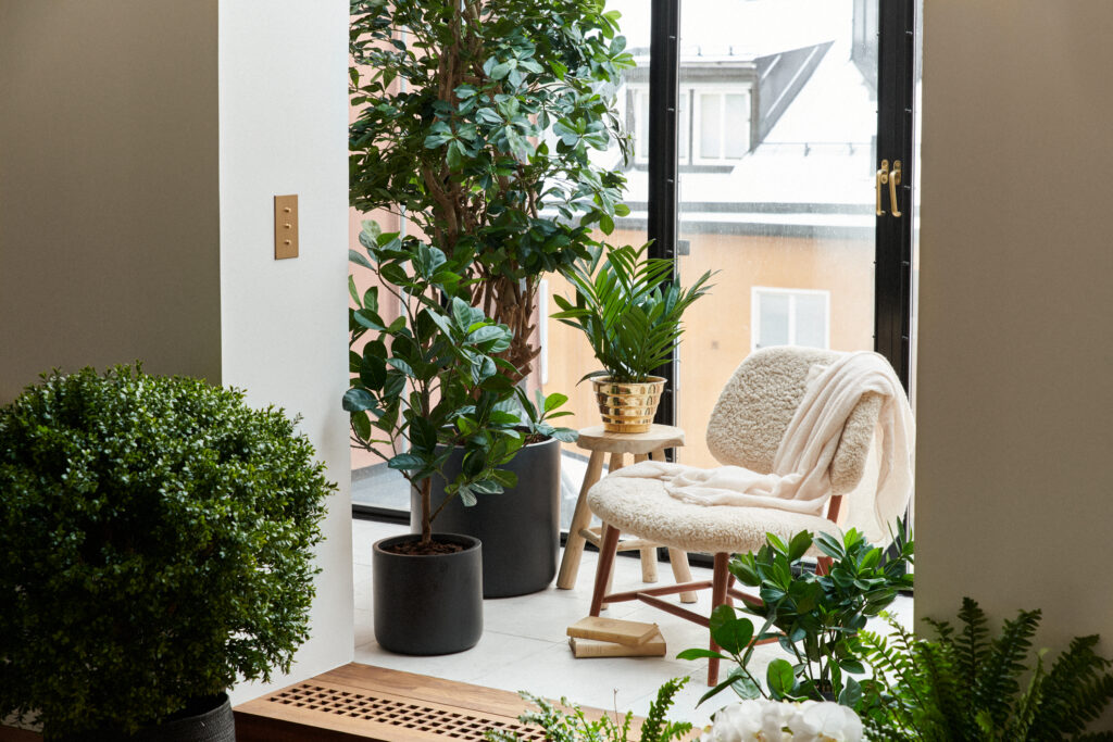 Bilden visar ett vardagsrum med konstväxter, växtväggar och konstblommor.